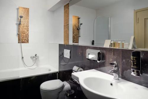 a bathroom with a sink and a toilet and a mirror at The Charles in Prague