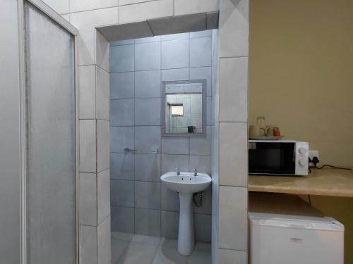 a small bathroom with a sink and a mirror at The Lantern Porch Guesthouse in Vryburg