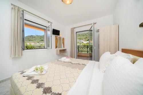 a white bedroom with a large bed and a window at Apartments Apollonio in Chrysi Ammoudia