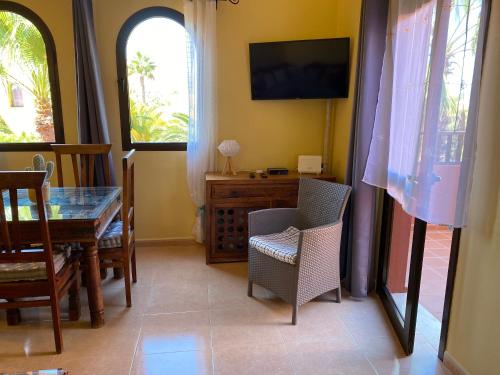 a dining room with a table and chairs and a television at Cosy apartment in Corralejo, shared pool, 55 m² in Corralejo