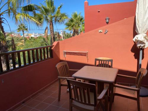 a table and chairs on a balcony with palm trees at Cosy apartment in Corralejo, shared pool, 55 m² in Corralejo