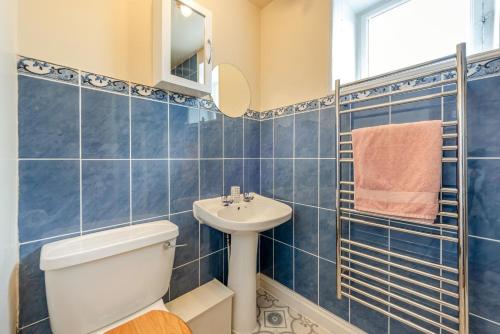 a blue tiled bathroom with a toilet and a sink at 1 Bed in Appledore oc-captv in Appledore