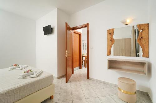 a bedroom with a bed and a mirror and a stool at Apartments Apollonio in Chrysi Ammoudia