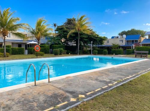 a swimming pool in a yard with palm trees at Charming Studio in Grand Baie, 60 m² with Shared Pool in Grand-Baie