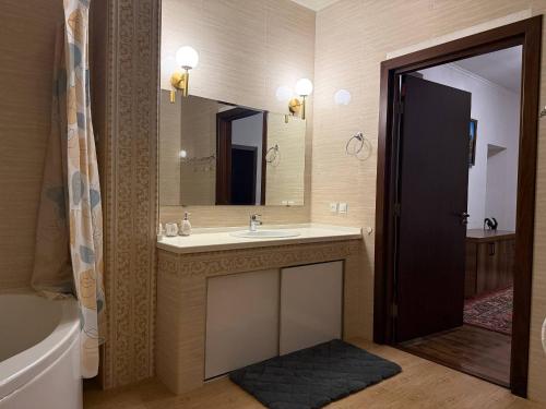 a bathroom with a sink and a mirror and a tub at Просторный дом с садом in Qŭyliq