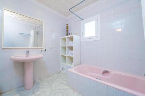 a bathroom with a pink tub and a sink at Can Fusteret in Son Serra de Marina