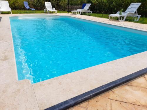 a swimming pool with blue water and white chairs at Charming Villa in Noto with Private Pool in Noto
