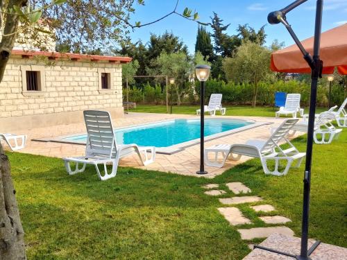 a pool with white chairs and a table and umbrella at Charming Villa in Noto with Private Pool in Noto