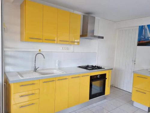 a kitchen with yellow cabinets and a sink at Appartement cosy avec piscine privée, Le François, 40 m² in Le François