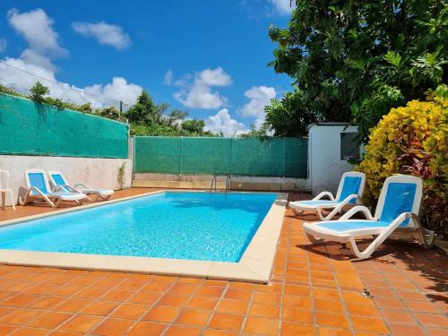 a swimming pool with lounge chairs and a fence at Appartement cosy avec piscine privée, Le François, 40 m² in Le François