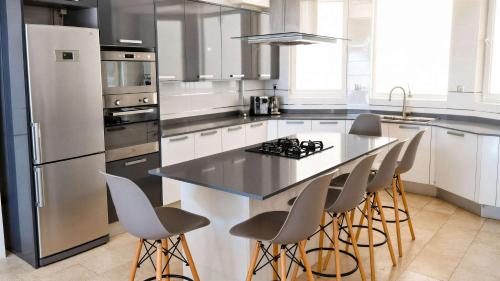 a kitchen with a counter with stools and a refrigerator at Sea-View Villa with Infinity Pool Algiers in Tipaza