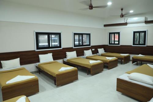 a room with four beds and windows at Kalathil Kshetra Inn in Guruvāyūr