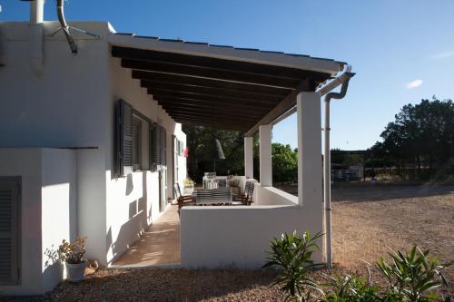 a white house with awning and a patio at Comfortable House in Formentera with Garden and Terrace in Sant Francesc Xavier