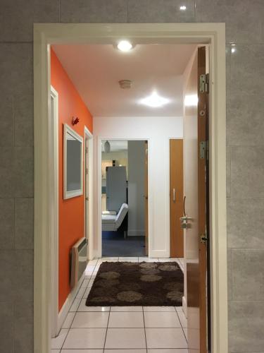 a hallway leading to a bathroom with orange walls at QuickSpaces Heart of the City in Manchester