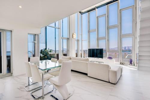 a living room with white furniture and a tv and windows at Penthouse With The Best Views! in Barcelona
