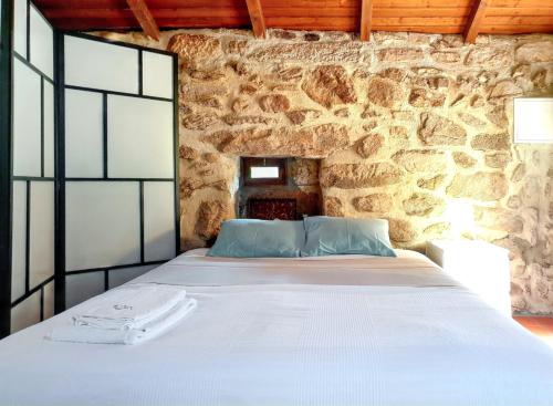 ein Bett in einem Zimmer mit einer Steinwand in der Unterkunft Cozy studio with mountain view - 20 m² - Águeda in Urgueira