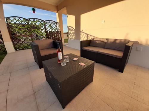 a patio with two couches and a table with a bottle of wine at Spacious house in Aldeia dos Pinheiros with pool in Azeitao