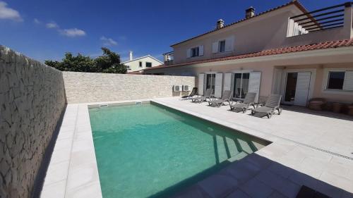 a swimming pool in front of a house at Spacious house in Aldeia dos Pinheiros with pool in Azeitao
