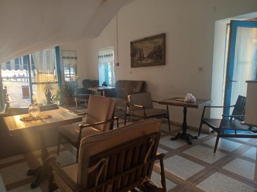 a living room with chairs and tables and windows at Okan Ali Gürsoy Otel in Ayvalık