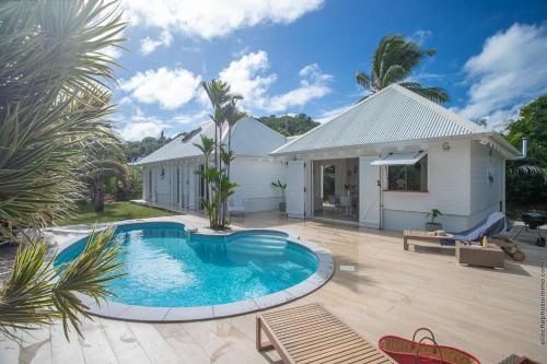 a backyard with a swimming pool and a house at Villa spacieuse à Hyacinthe, Le Robert avec piscine privée in Le Robert