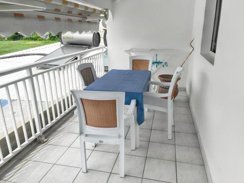 a balcony with a blue table and chairs on it at Appartement convivial au Moule avec jardin clôturé in Le Moule