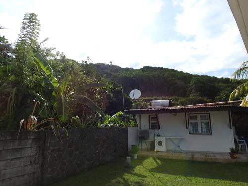 a small white house with a hill in the background at Studio charmant à Le Robert - 17 m² avec Piscine partagée in Le Robert
