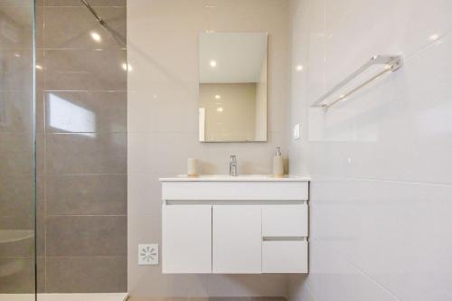 a white bathroom with a sink and a shower at Villa Flamingo - BY SCH in Nadadouro