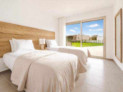 two beds in a bedroom with a large window at Villa Flamingo - BY SCH in Nadadouro