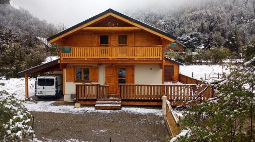 a log cabin with a porch in the snow at Chalet Enchanteur à Venosc avec Vue Panoramique et Jacuzzi in Vénosc