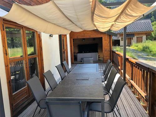 a table with chairs and an umbrella on a deck at Chalet Enchanteur à Venosc avec Vue Panoramique et Jacuzzi in Vénosc