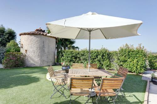 a table and chairs with an umbrella in a yard at Villa élégante à Fréjus, Piscine in Fréjus