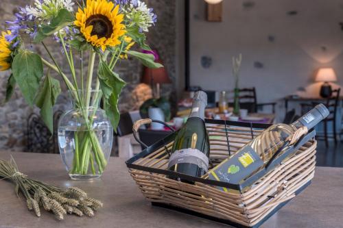 a basket of wine and a vase with flowers on a table at Maison avec piscine privée à La Digne-d'Aval in La Digne-dʼAval