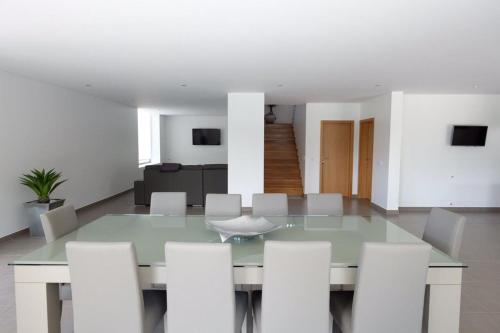 a dining room with a glass table and white chairs at Luxurious Villa in Vieira do Minho – Private Pool in Vieira do Minho