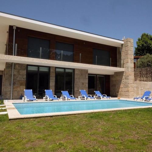 a house with a swimming pool and some chairs at Luxurious Villa in Vieira do Minho – Private Pool in Vieira do Minho