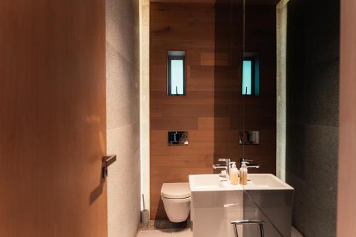 a bathroom with a white toilet and a sink at The Pool House in Gqeberha
