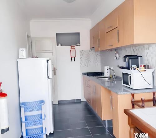 a kitchen with a white refrigerator and wooden cabinets at Bright apartment in Almada with shared pool in Almada