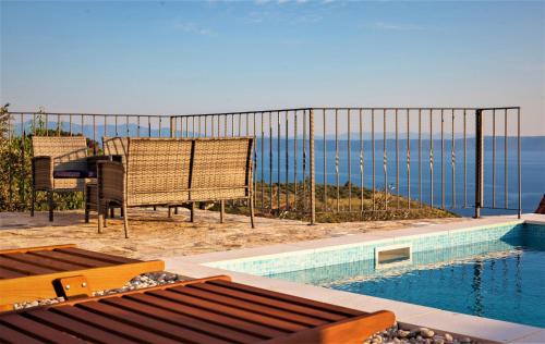 a swimming pool with chairs and a fence with a view of the ocean at Elegant villa in Podgora with private pool and sea view in Podgora