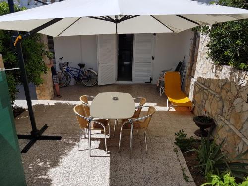 a white table and chairs under an umbrella at Modern apartment with sea view in Pag, 40 sqm in Pag