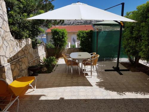 a white table and chairs under an umbrella at Modern apartment with sea view in Pag, 40 sqm in Pag