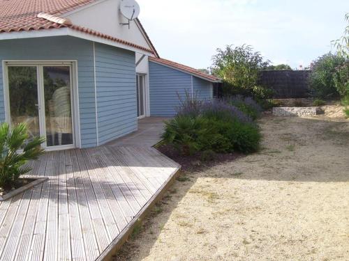 a house with a wooden walkway leading into a yard at Villa ensoleillée à Saint Hilaire de Riez avec piscine privée in Saint-Hilaire-de-Riez