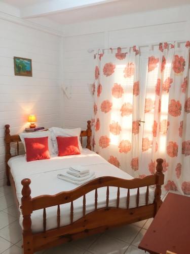 a bedroom with a bed with red pillows at Villa Enchantée avec Vue sur mer et Piscine au Carbet in Le Carbet