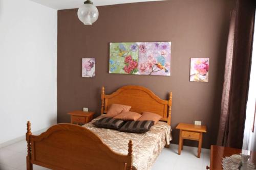 a bedroom with a wooden bed and paintings on the wall at Welcoming apartment with mountain view in El Paso