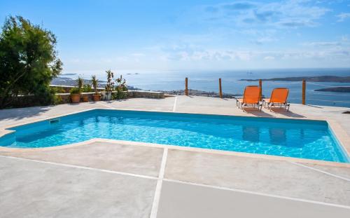 a swimming pool with two chairs and the ocean at Charming House in Paros, 90 m² with Shared Pool in Parikia