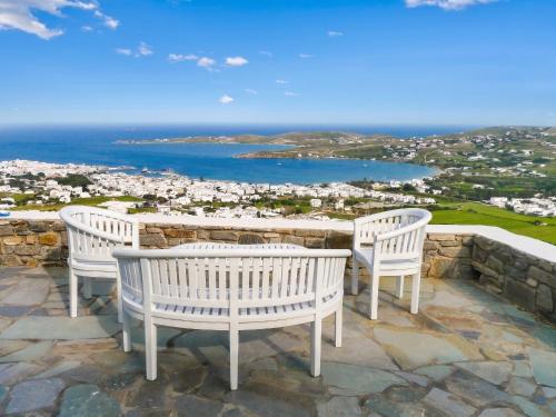 two white chairs sitting on a patio overlooking the ocean at Charming House in Paros, 90 m² with Shared Pool in Parikia