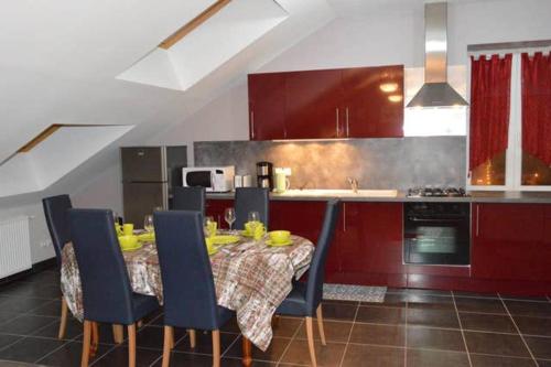 a kitchen with a table and chairs and a kitchen with red cabinets at Appartement chaleureux à Gérardmer avec parking privé. in Gérardmer