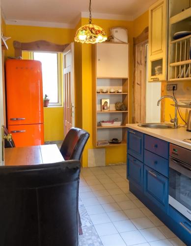 a kitchen with yellow walls and blue cabinets and a table at Spacious House in Central Sofia with Garden in Sofia