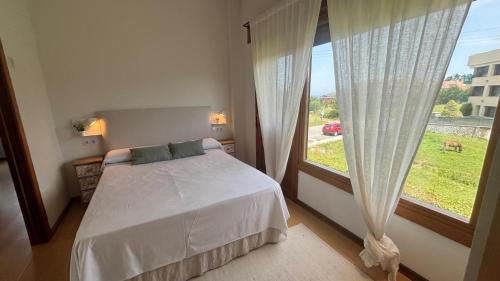 a bedroom with a bed and a large window at AP TXALUPA II in Barro de Llanes