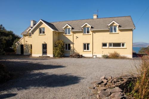 a large yellow house with a gravel driveway at Spacious house with sea and mountain views, Co. Kerry in Kells