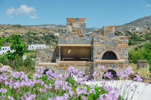 a stone building in a field with purple flowers at Spacious house with sea view in Ag. Arsenios, garden in Glinádhon