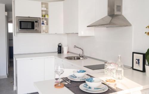 a white kitchen with two cups and plates on a counter at Charming Apartment in Tías + Pool in Tías